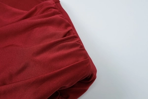 Detailed macro view of the ruched texture and burgundy pleated fabric of the dress