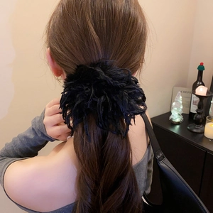 Détail d'un chouchou en fausse fourrure noire duveteuse porté sur une coiffure en queue