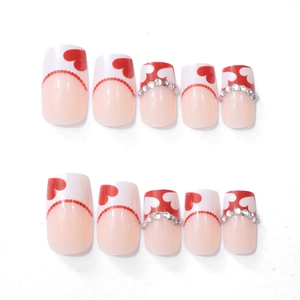 Detail of square false nails with red hearts, dots, and sparkling rhinestones
