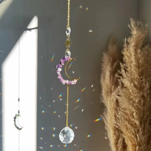Detail of amethyst moon sun catcher reflecting rainbow light on a golden metal chain