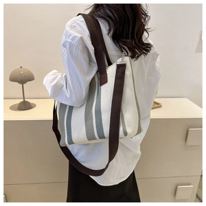 Detailed view of the striped canvas tote bag with brown woven straps on the back of a model