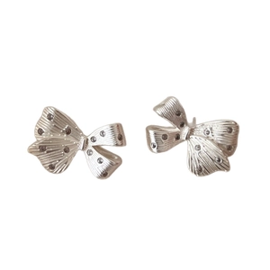 Silver bow knot stud earrings with delicate ribbon texture and sparkling crystal accents