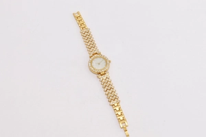 Macro shot of gold women's watch featuring a crystal-encrusted bezel and white pearl dial