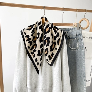 Detail eines Seidenschals mit Leopardenmuster, gebunden an ein weißes Sweatshirt