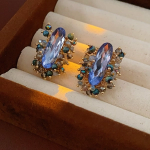 Nahaufnahme von Vintage-Ohrringen mit blauen Kristallen und Perlenverzierung im Schmuckkästchen