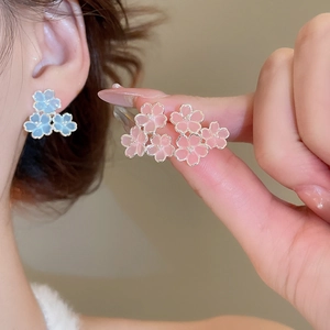 Détails de boucles d'oreilles fleurs en résine rose et bleue portées par un mannequin