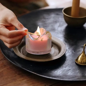 Rosa Duftkerze mit Goldfolie in einem mattierten Glasbehälter mit natürlichen Wellen