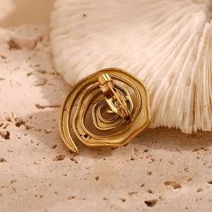 Golden swirl spiral brooch plated in 18K gold with white diamonds on travertine