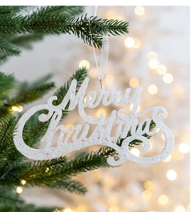 White glitter Merry Christmas letter hanging ornament on a decorated Christmas tree