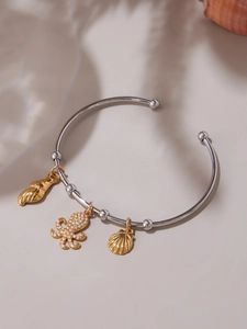 Detail of silver open bangle with gold octopus and seashell charms with cubic zirconia