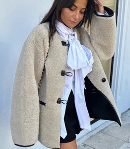 Détail de la veste en peau lainée beige avec boutons basculants et passepoil noir contrasté