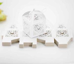 Macro detail of laser-cut heart and vine patterns on a white wedding candy gift box