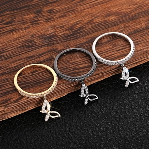 Detailed view of butterfly pendant rings with zircon inlay in gold, silver, and black