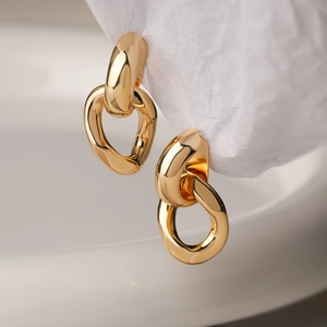 Minimalist geometric gold earrings with interlocking double rings on textured paper