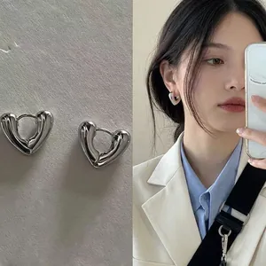 Minimalist silver heart-shaped hoop earrings with 3D design shown on model and product view