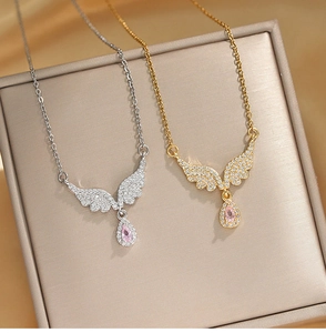 Detailed close-up of gold and silver angel wing necklaces with pink drop-shaped zircon