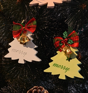 Detail of white and green Christmas tree ornaments with festive bows and golden bells