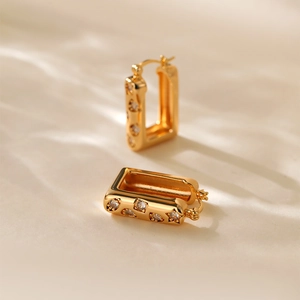 Detailed macro view of gold plated earrings with star zircon stones and textured finish