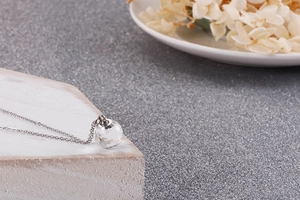 Detail of multi-faceted crystal ball pendant on silver stainless steel chain necklace