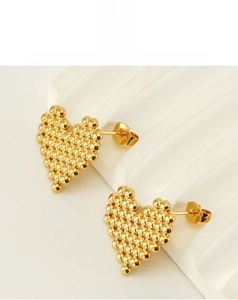 Détails de boucles d'oreilles cœur dorées avec une texture de perles travaillée