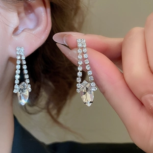 Close-up of silver tassel earrings featuring sparkling teardrop crystal pendants