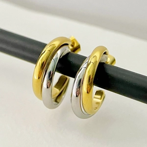 Macro view of bicolor gold and silver interlaced double hoop earrings in polished steel