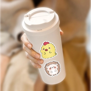 Close-up of white travel mug decorated with cute cartoon chick and hedgehog stickers