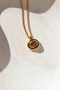 Close-up of a vintage oval tiger eye stone pendant on a delicate 18K gold plated chain