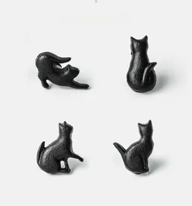 Detailed view of black cast iron cat-shaped handles with a rustic matte finish texture