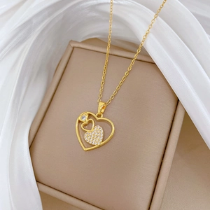 Detailed close-up of hollow gold heart necklace with crystal zircon pavé on beige box