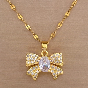 Detail of gold titanium steel bow necklace with sparkling crystals and central oval gemstone