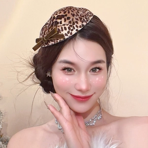 Close-up of leopard print fabric beret with dark brown velvet bow and luxury jewelry details