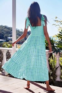 Outdoor view of back design on mint green tiered floral midi dress with smocked detail