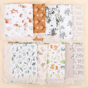 Close-up of soft cotton muslin baby swaddle blankets with tassels and animal patterns