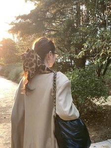 Woman from behind wearing a leopard print scrunchie in natural sunset lighting