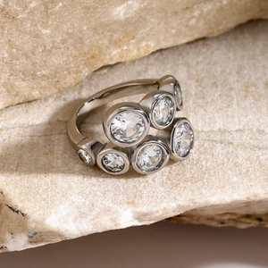 Macro shot of silver zircon open ring with irregular round stones on light stone base