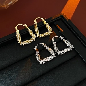 Macro detail of U-shaped gold and silver earrings with inlaid cubic zirconia on black leather