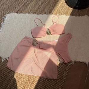 Detailed view of pink three-piece bikini set with honeycomb texture and metal buckles