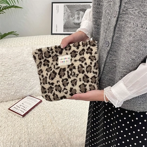 Detail of plush leopard print cosmetic bag featuring a designer woven label for storage