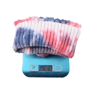 Women's tie-dye knit beanie in pink and blue colors shown on a digital scale weighing 121g