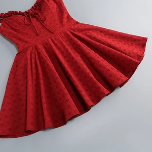 Detailed view of red hollow-out embroidery and lace-up neckline on a cotton mini dress