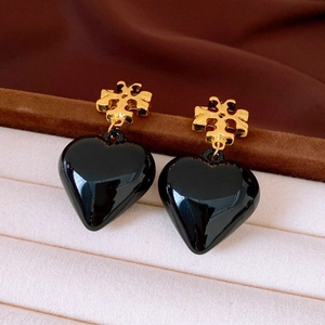 Close-up of vintage gold totem stud with a glossy black heart drop pearl earring