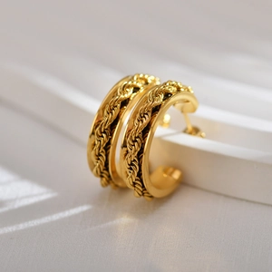 Macro detail of gold-plated twisted rope earrings with smooth border and C-shaped design