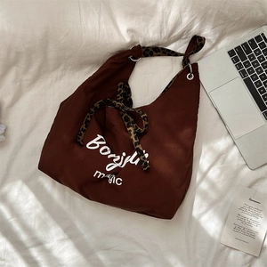 Brown nylon tote bag with Bonjour text and leopard print strap in a lifestyle setting