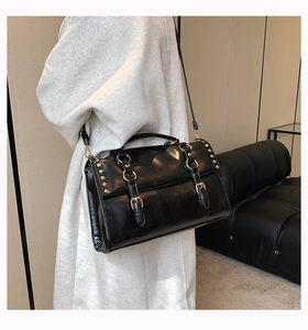 Detailed view of black vintage satchel bag with silver studs and double strap buckles