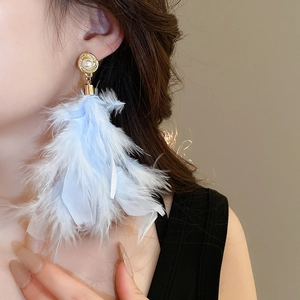 Close-up of light blue feather earrings with gold frame and inlaid white pearl