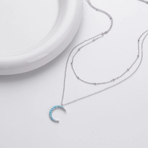 Macro detail of silver S925 double layer necklace featuring a blue moon crescent pendant