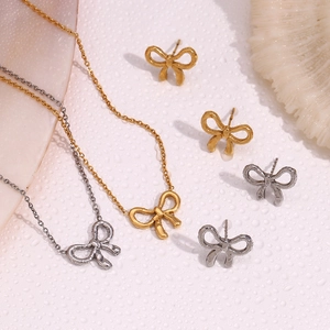 Detailed view of 18K gold and silver bow pendant necklaces and matching stud earrings