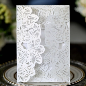 Detailed laser-cut floral pattern on a pearlescent white wedding invitation card