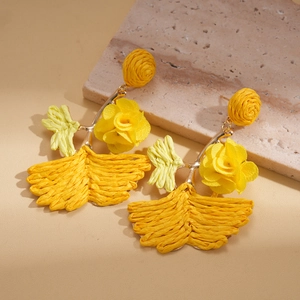 Detail of yellow raffia flower earrings with woven textures and natural petals